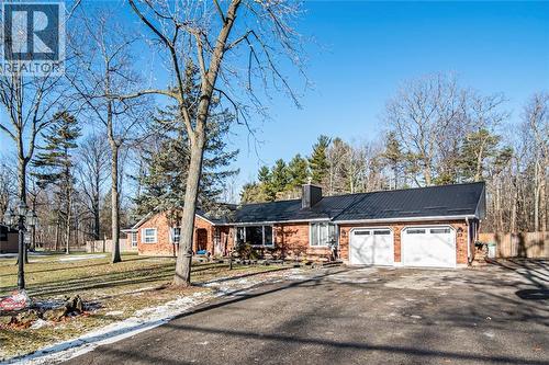 View of front facade with brick siding, driveway, a chimney, and a garage - 7087 Rainham Road, Dunnville, ON - Outdoor
