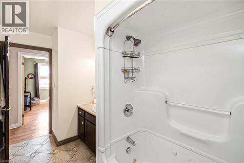 Bathroom featuring vanity, a combined bath / shower with jetted tub, and stone tile floors - 7087 Rainham Road, Dunnville, ON - Indoor Photo Showing Bathroom