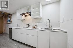 Kitchen with open shelves, white cabinetry, light countertops, and light wood-style floors - 