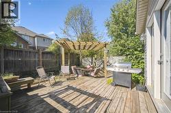 Wooden terrace with a fenced backyard, grilling area, and a pergola - 