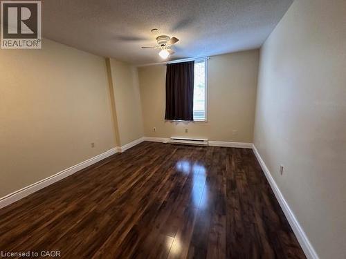 Empty room featuring dark wood finished floors, a textured ceiling, a ceiling fan, and a baseboard radiator - 35 Green Valley Drive Unit# 414, Kitchener, ON - Indoor Photo Showing Other Room