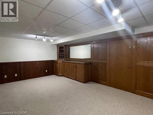 Finished basement with a paneled ceiling, light colored carpet, wooden walls, a wainscoted wall, and track lighting - 214 Benesfort Crescent, Kitchener, ON - Indoor