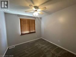 Empty room featuring dark colored carpet and ceiling fan - 