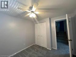 Unfurnished bedroom with dark carpet, a closet, and ceiling fan - 