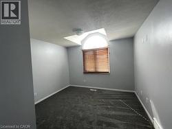 Empty room featuring a textured ceiling, dark carpet, and a baseboard radiator - 