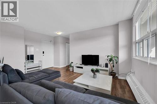 Living room featuring a baseboard radiator, wood finished floors, and baseboards - 15 Albright Road Unit# 811, Hamilton, ON 