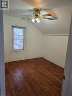 Spare room featuring vaulted ceiling, dark wood-style flooring, and a ceiling fan - 