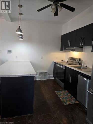 Kitchen with dark cabinetry, hanging light fixtures, stove, dishwasher, and exhaust hood - 10 Centre Street, Elmira, ON - Indoor Photo Showing Kitchen With Double Sink