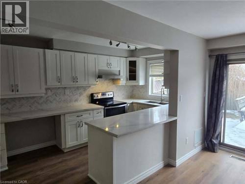 Kitchen featuring stainless steel electric range oven, white cabinetry, rail lighting, and dark wood finished floors - 185 Sulmona Drive, Hamilton, ON - Indoor Photo Showing Kitchen With Double Sink