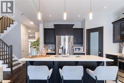 Kitchen with backsplash, stainless steel appliances, a breakfast bar area, dark cabinetry, and recessed lighting - 