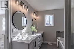 Bathroom with double vanity, a tub to relax in, and dark tile patterned flooring - 