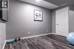 Workout room featuring dark wood-style flooring and baseboards - 