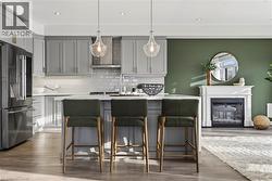 Kitchen featuring gray cabinetry, high quality fridge, pendant lighting, tasteful backsplash, and a breakfast bar area - 