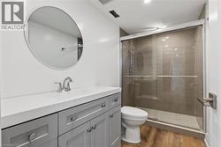 Full bath featuring vanity, a stall shower, and light wood-style flooring - 