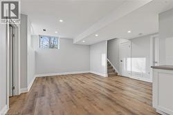 Below grade area featuring light wood-style flooring, stairs, and recessed lighting - 