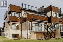 Back of property with stone siding, a lawn, and a sunroom - 