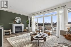 Living area featuring a glass covered fireplace, wood finished floors, healthy amount of natural light, and recessed lighting - 