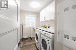 Laundry room featuring dark wood-type flooring, cabinet space, washing machine and clothes dryer, a heating unit, and a baseboard heating unit - 