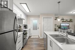 Suite Kitchen with white cabinetry, stainless steel appliances, and light countertops - 