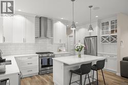 Kitchen with stainless steel appliances, glass insert cabinets, wall chimney exhaust hood, a kitchen island, and a kitchen bar - 