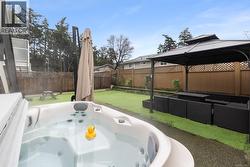 Fenced backyard featuring outdoor lounge area, a hot tub, a patio, and a gazebo - 