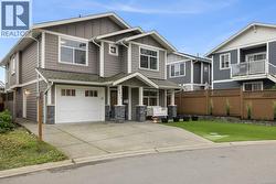 Craftsman-style house featuring board and batten siding, driveway, stone siding, an attached garage, and roof with shingles - 