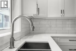 Kitchen view of white cabinetry, light stone counters, and tasteful backsplash - 