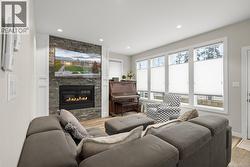 Living room with light wood-style floors, a stone fireplace, and recessed lighting - 