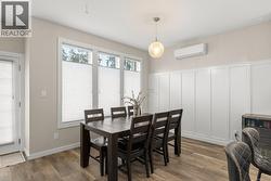 Dining area featuring dark wood finished floors, a wall mounted AC, and a decorative wall - 