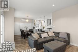 Living room with wood finished floors, a decorative wall, a wall unit AC, and a wainscoted wall - 