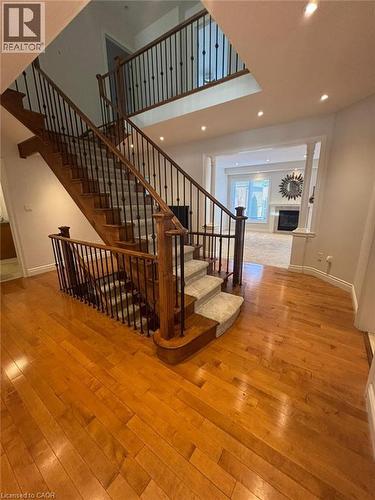 Stairs with hardwood / wood-style flooring, a glass covered fireplace, ornate columns, a high ceiling, and recessed lighting - 93 Tremaine Drive, Kitchener, ON - Indoor Photo Showing Other Room