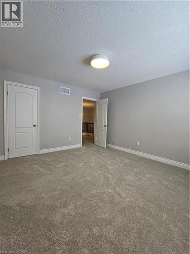 Unfurnished bedroom featuring carpet and a textured ceiling - 93 Tremaine Drive, Kitchener, ON - Indoor Photo Showing Other Room