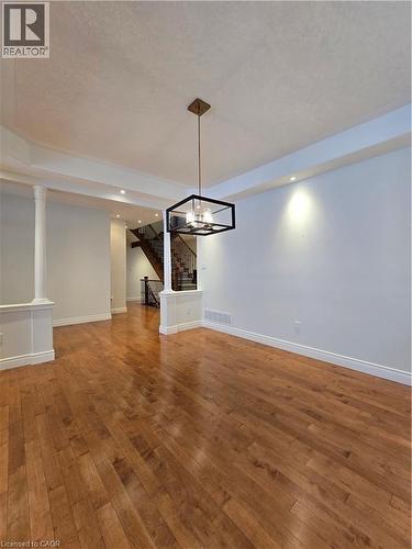 Unfurnished dining area with stairway, recessed lighting, hardwood / wood-style flooring, a chandelier, and decorative columns - 93 Tremaine Drive, Kitchener, ON - Indoor Photo Showing Other Room