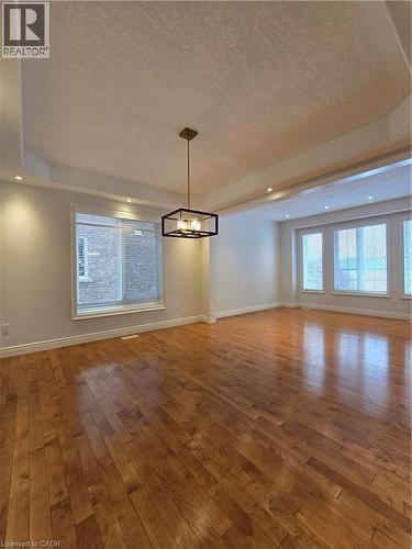 Unfurnished dining area featuring a tray ceiling, a chandelier, hardwood / wood-style floors, a textured ceiling, and recessed lighting - 93 Tremaine Drive, Kitchener, ON - Indoor Photo Showing Other Room