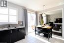 Kitchen featuring dark cabinets, hanging light fixtures, light stone counters, light tile patterned floors, and backsplash - 49 Eberhardt Drive, Wasaga Beach, ON  - Indoor Photo Showing Kitchen With Double Sink 