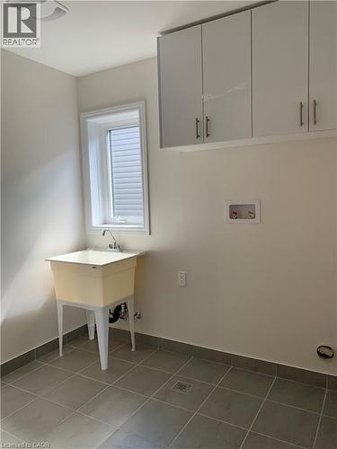 Washroom featuring hookup for a washing machine, light tile patterned floors, and cabinet space - 49 Eberhardt Drive, Wasaga Beach, ON - Indoor