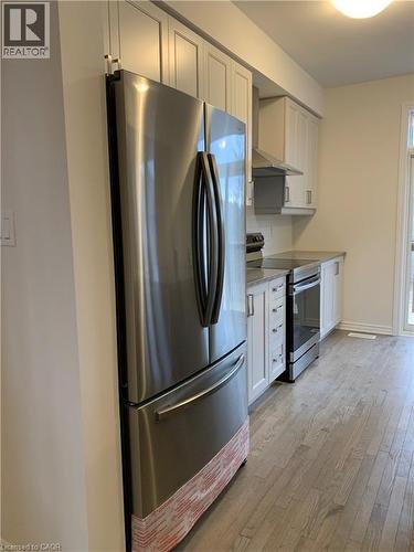 Kitchen featuring stainless steel appliances, light wood-style flooring, wall chimney range hood, and white cabinetry - 49 Eberhardt Drive, Wasaga Beach, ON - Indoor Photo Showing Kitchen