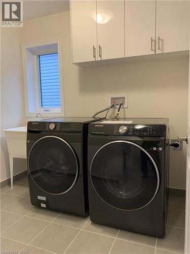 Washroom with light tile patterned floors, cabinet space, and washing machine and clothes dryer - 49 Eberhardt Drive, Wasaga Beach, ON - Indoor Photo Showing Laundry Room