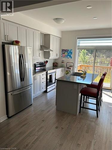 Kitchen with appliances with stainless steel finishes, exhaust hood, a kitchen bar, a kitchen island, and dark countertops - 49 Eberhardt Drive, Wasaga Beach, ON - Indoor Photo Showing Kitchen