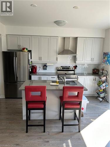 Kitchen with fridge, a kitchen breakfast bar, range, range hood, and backsplash - 49 Eberhardt Drive, Wasaga Beach, ON - Indoor Photo Showing Kitchen
