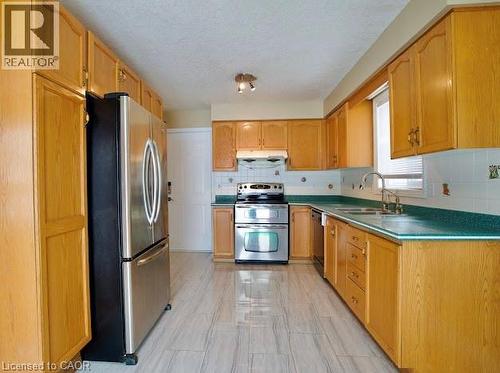 Kitchen with stainless steel appliances, tasteful backsplash, a textured ceiling, dark countertops, and under cabinet range hood - 109 Beechmanor Crescent, Kitchener, ON - Indoor Photo Showing Kitchen