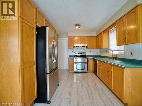 Kitchen featuring appliances with stainless steel finishes, decorative backsplash, a textured ceiling, and under cabinet range hood - 109 Beechmanor Crescent, Kitchener, ON - Indoor Photo Showing Kitchen