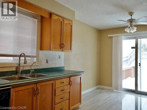 Kitchen with dark countertops, brown cabinetry, tasteful backsplash, dishwasher, and a ceiling fan - 109 Beechmanor Crescent, Kitchener, ON - Indoor Photo Showing Kitchen With Double Sink