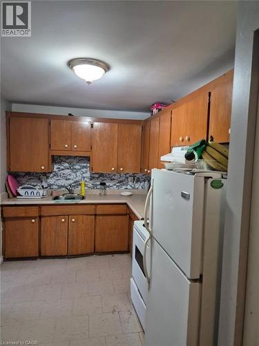 Kitchen featuring white appliances, light countertops, brown cabinetry, and backsplash - 76 Brybeck Crescent Unit# 204, Kitchener, ON - Indoor Photo Showing Kitchen With Double Sink