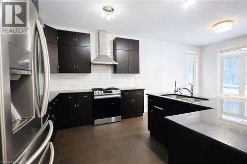 Kitchen with stainless steel appliances, dark cabinetry, wall chimney exhaust hood, backsplash, and dark tile patterned flooring - 127 Elmbank Trail Unit# Upper, Kitchener, ON - Indoor Photo Showing Kitchen With Double Sink With Upgraded Kitchen