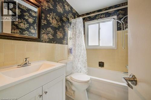 Bathroom featuring vanity, wallpapered walls, shower / bathtub combination with curtain, tile walls, and a wainscoted wall - 33 Garland Crescent, London, ON - Indoor Photo Showing Bathroom