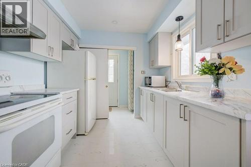 Kitchen with white electric stove, wall chimney range hood, plenty of natural light, and stainless steel microwave - 33 Garland Crescent, London, ON - Indoor Photo Showing Kitchen
