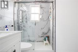 Full bath featuring vanity and a marble finish shower - 