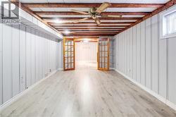 Below grade area featuring french doors, wood finished floors, a ceiling fan, and wood walls - 