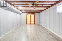 Empty room featuring ceiling fan, light wood finished floors, and french doors - 